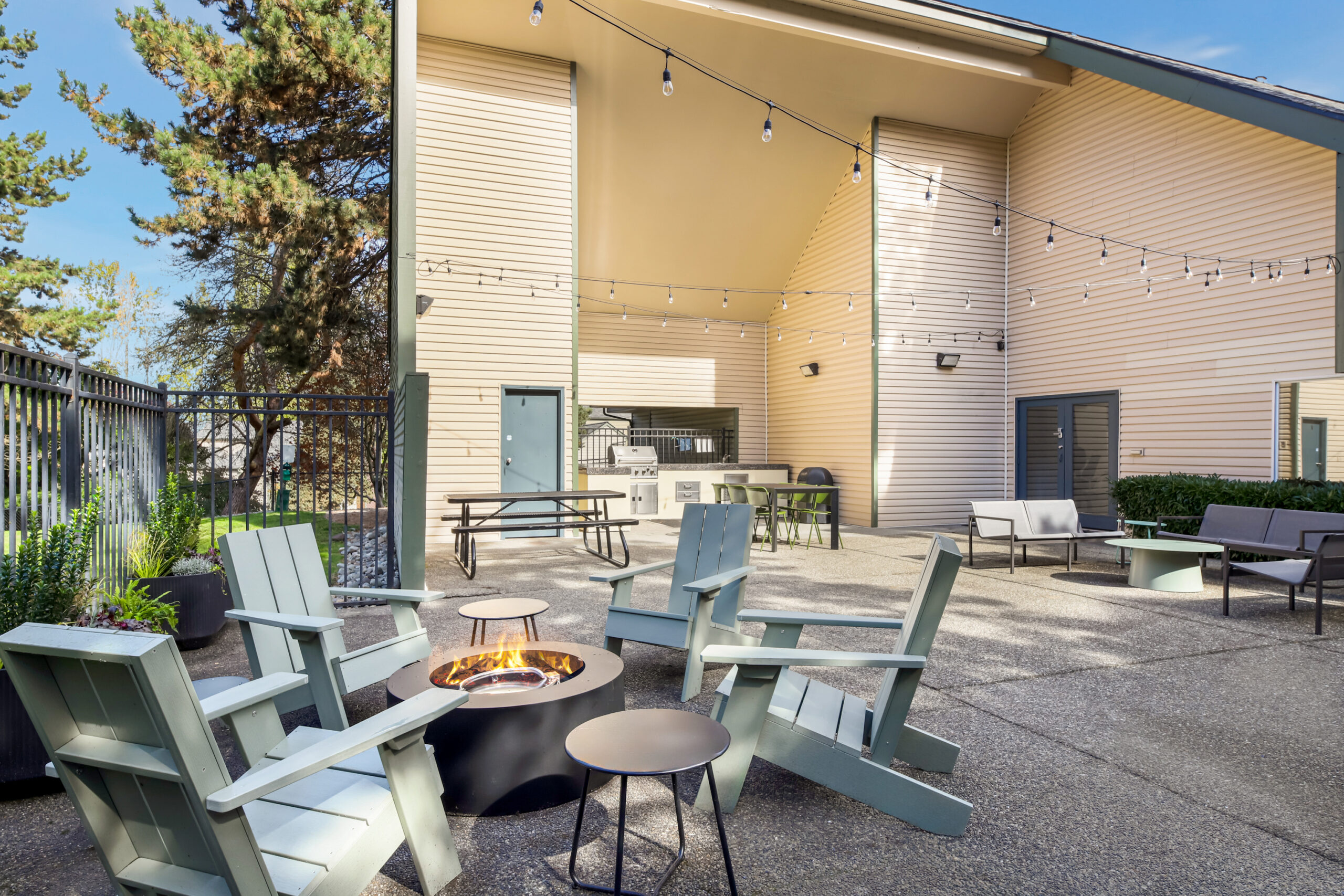 A landscaped common area with BBQ grills, cornhole boards, and comfortable chairs, giving the feel of a private backyard.